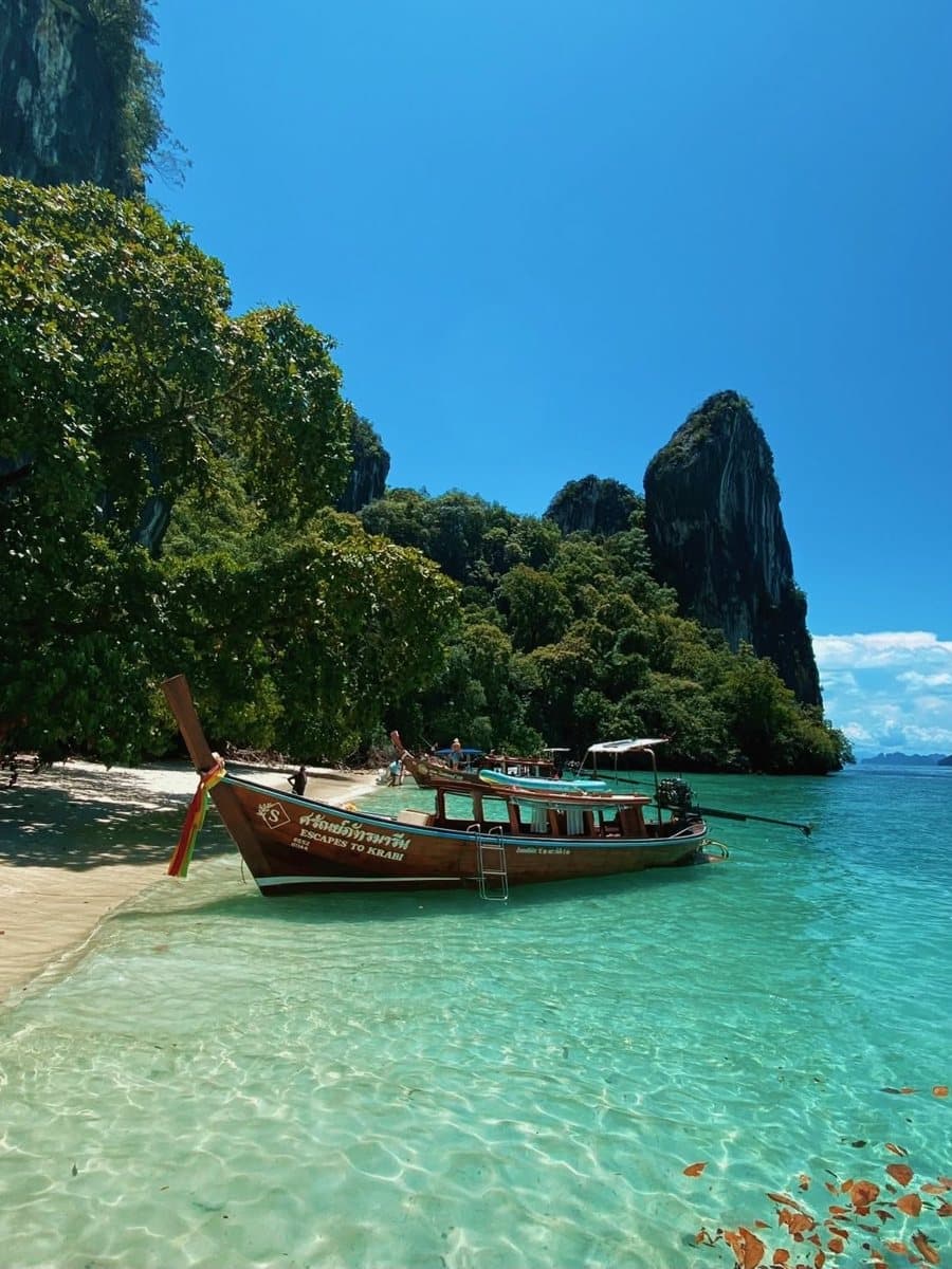 Krabi Escape longtail moored on a white-sand beach with limestone cliffs