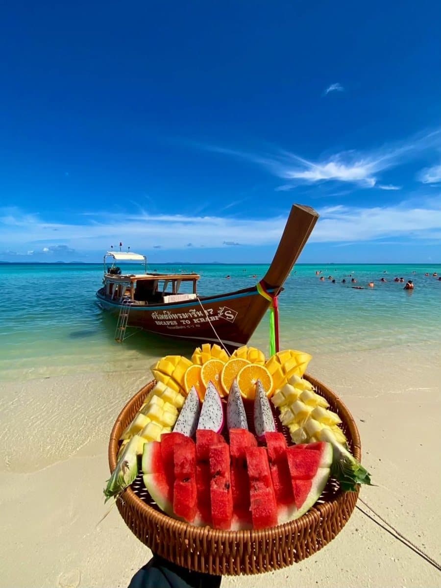 Tropical fruit basket on the beach in front of a Krabi Escape longtail