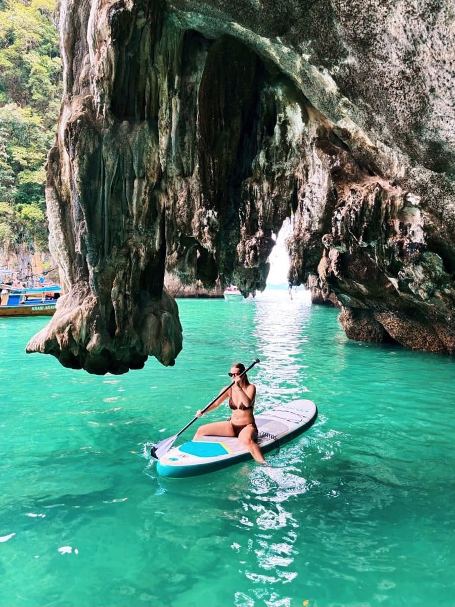 Guest on a paddle board beneath limestone rock formations