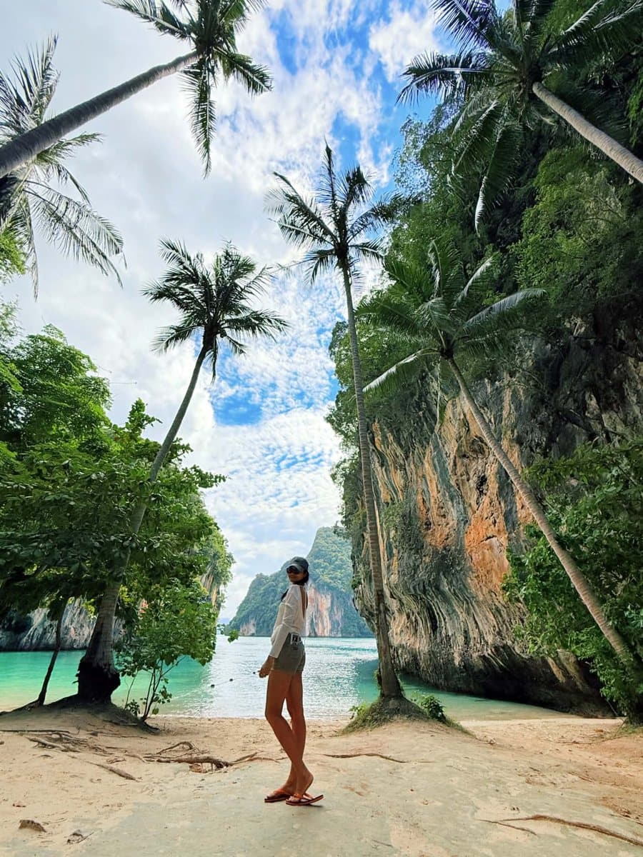 Guest on a palm-lined beach between limestone cliffs